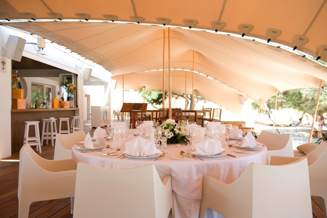 Banquete bajo carpa con mesas vestidas y vistas al exterior