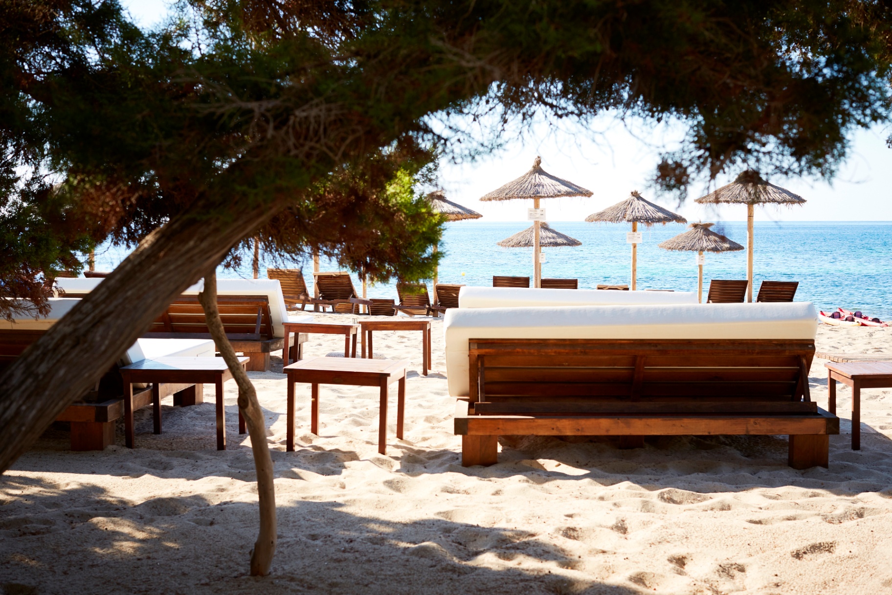 Daybeds frente a las sombrillas de paja al borde del mar